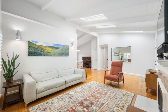 living area with lofted ceiling with skylight, baseboards, and light wood-type flooring