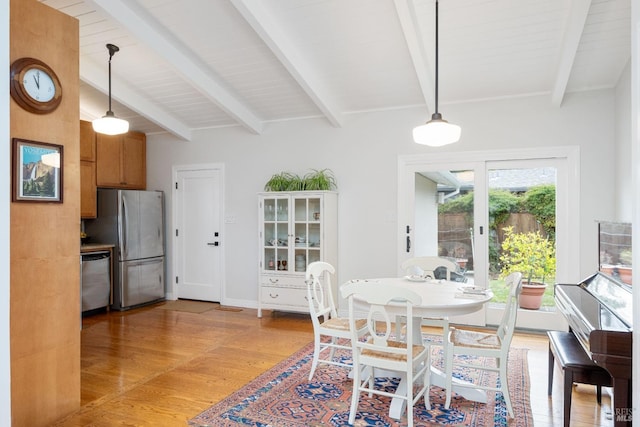 dining room with beamed ceiling, baseboards, and light wood finished floors