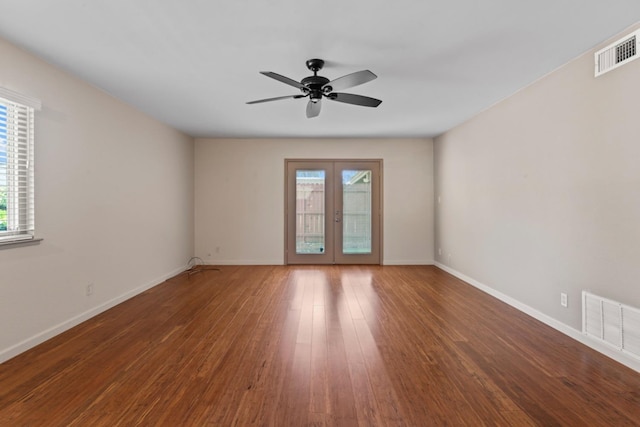 empty room featuring visible vents, baseboards, wood finished floors, and french doors