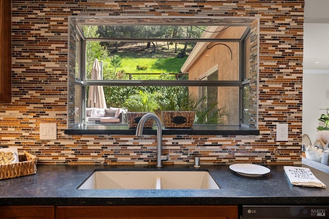 kitchen featuring a sink, dishwashing machine, dark countertops, and decorative backsplash