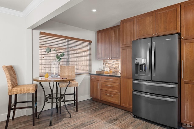 kitchen with backsplash, dark wood finished floors, stainless steel fridge, brown cabinetry, and crown molding