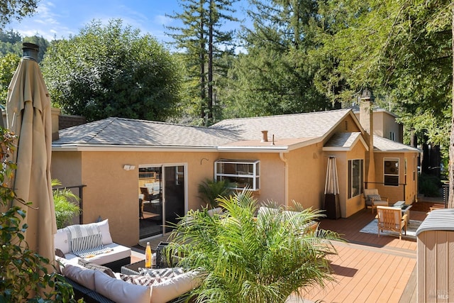 rear view of house with stucco siding, a chimney, a deck, and outdoor lounge area