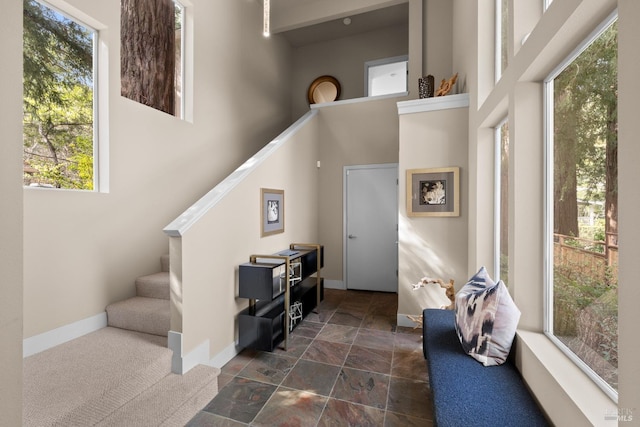 interior space featuring stairway, a high ceiling, baseboards, and stone finish floor