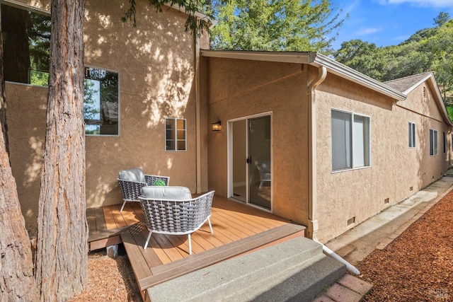 rear view of property featuring crawl space, a wooden deck, and stucco siding