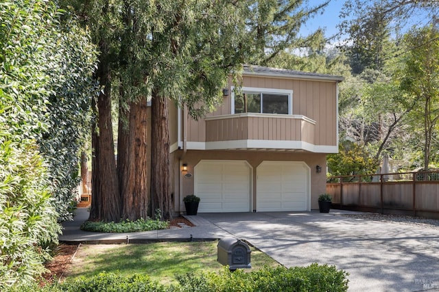 view of front of property featuring concrete driveway, a balcony, an attached garage, and fence