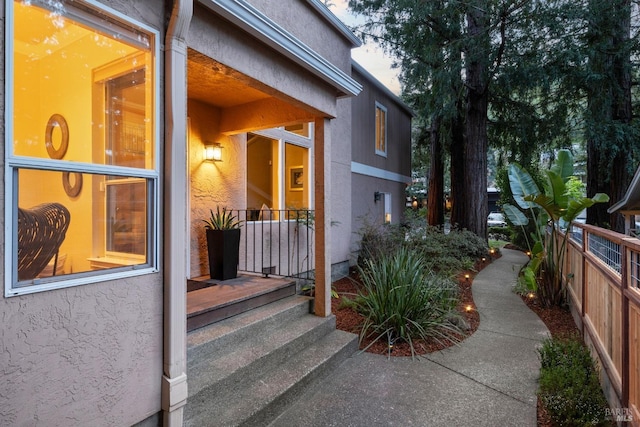 entrance to property with stucco siding and fence