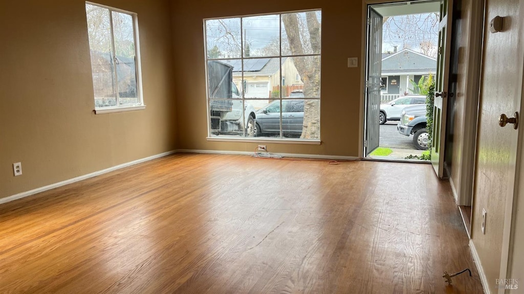 spare room featuring wood finished floors, baseboards, and a wealth of natural light