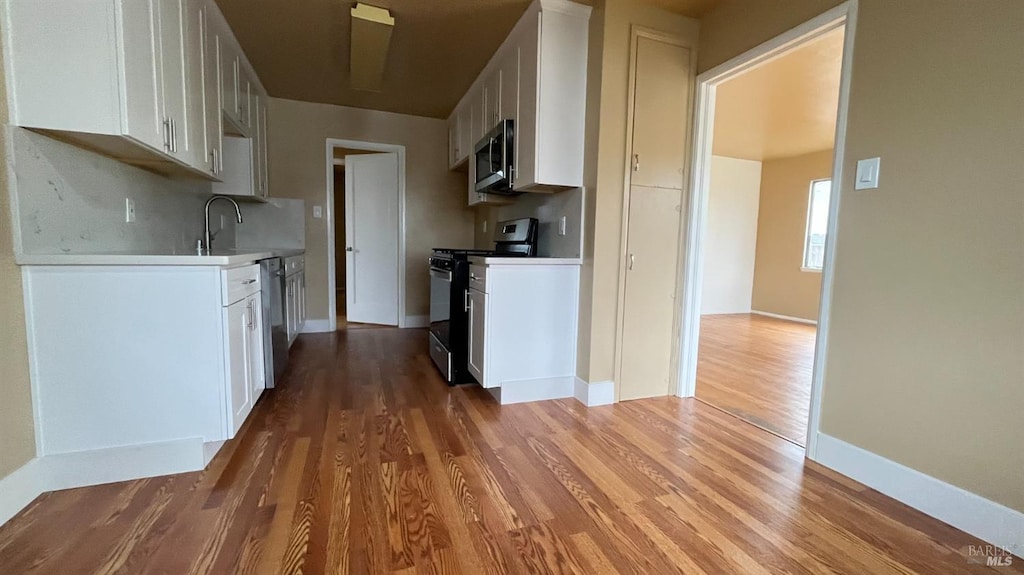 kitchen featuring a sink, light wood-style floors, appliances with stainless steel finishes, white cabinets, and light countertops