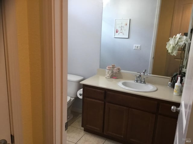 half bath featuring tile patterned flooring, vanity, and toilet