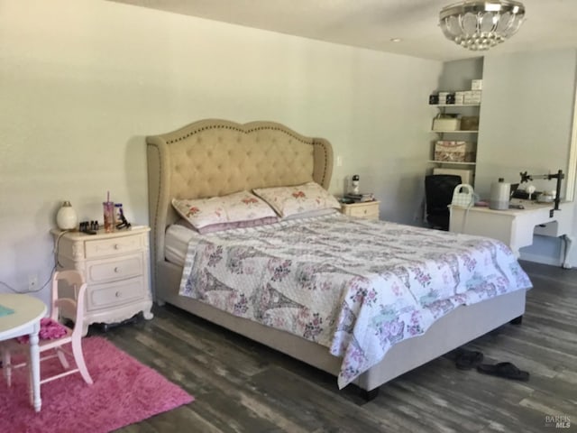 bedroom featuring a notable chandelier and dark wood-type flooring