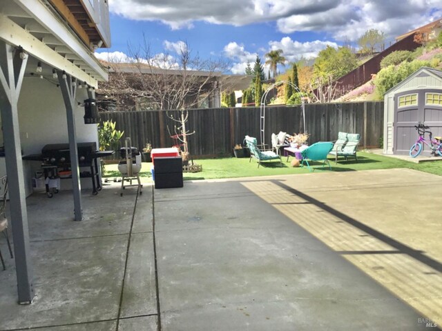 view of patio with a fenced backyard, a shed, area for grilling, and an outdoor structure