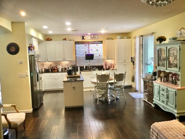 kitchen with white cabinets, a kitchen island, tasteful backsplash, dark wood-style floors, and freestanding refrigerator