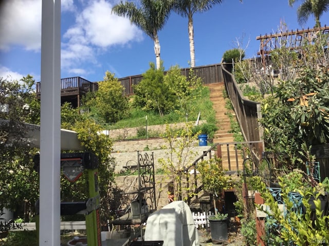 view of yard featuring a garden, fence, and stairs