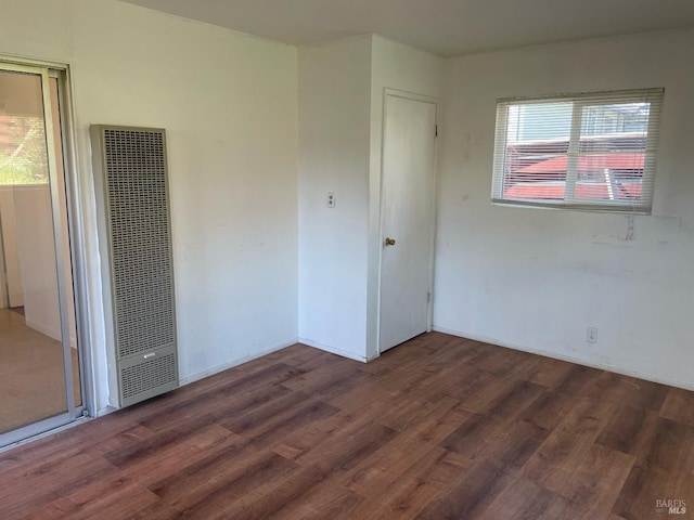 unfurnished bedroom featuring baseboards, wood finished floors, and a heating unit