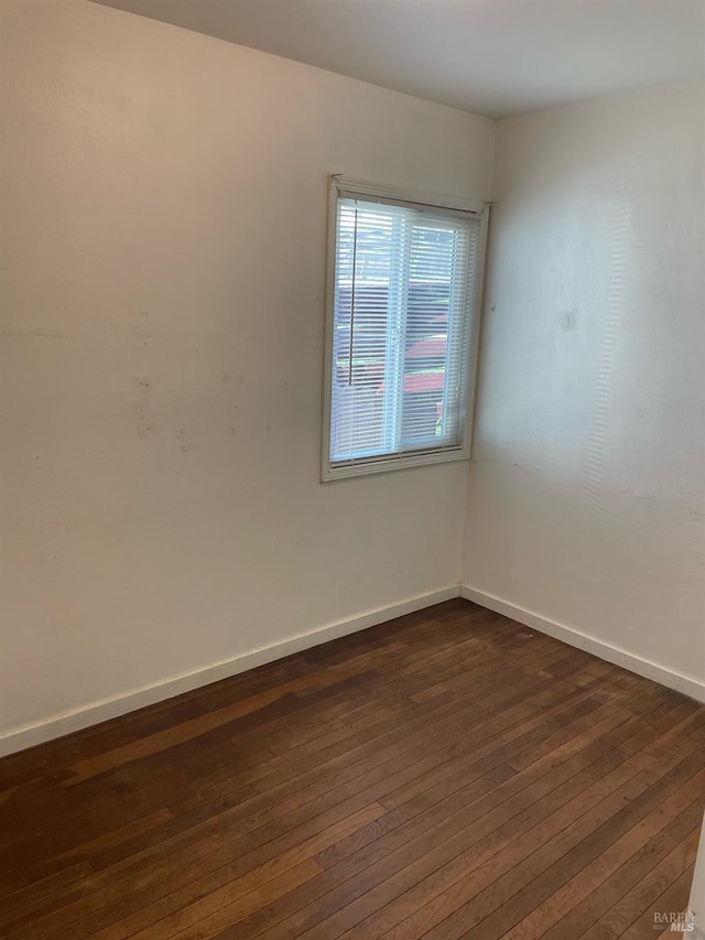 unfurnished room with baseboards and dark wood-style flooring