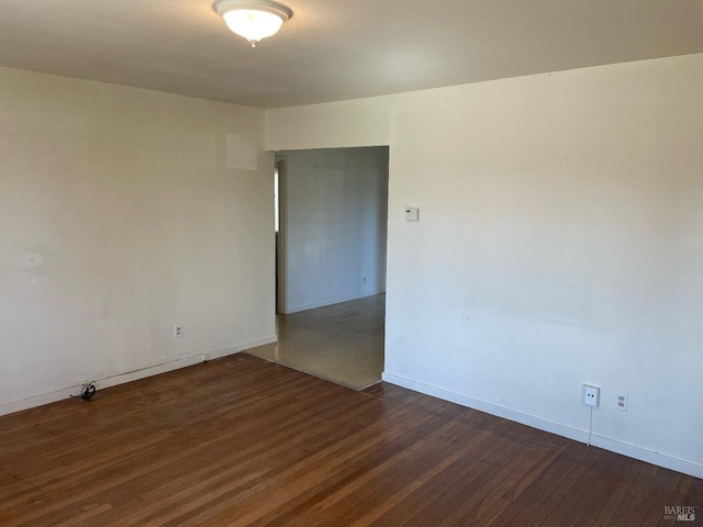 spare room featuring baseboards and hardwood / wood-style flooring