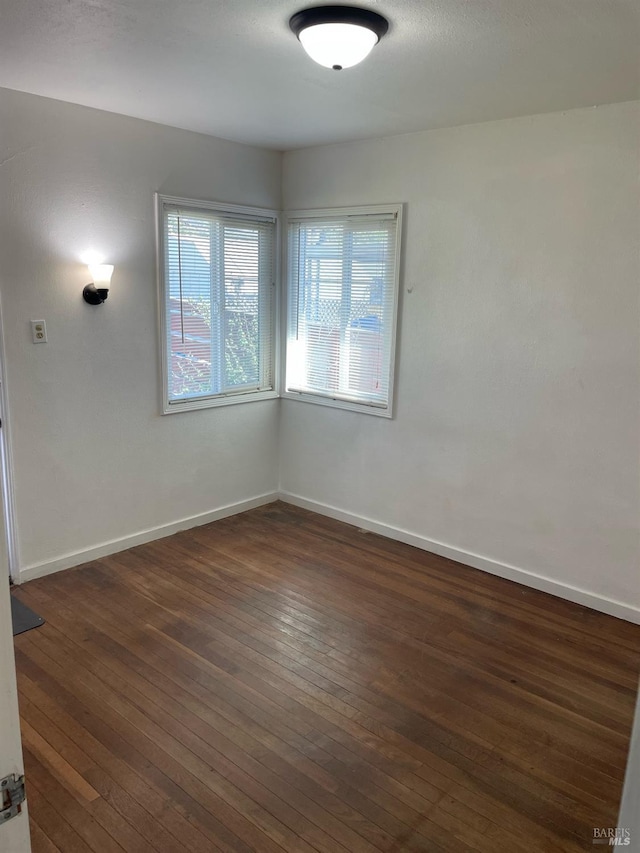 spare room with dark wood finished floors and baseboards