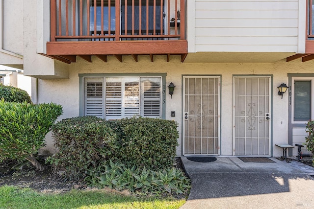 property entrance with stucco siding and a balcony