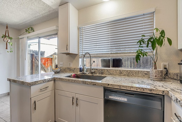 kitchen with a sink, a textured ceiling, white cabinets, dishwasher, and a textured wall