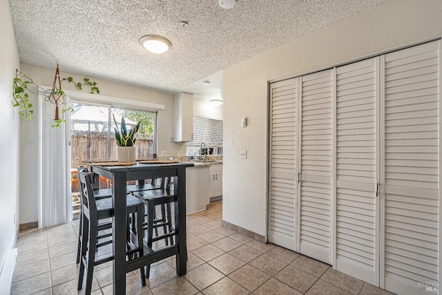 dining area featuring light tile patterned floors, baseboards, a textured ceiling, and a textured wall