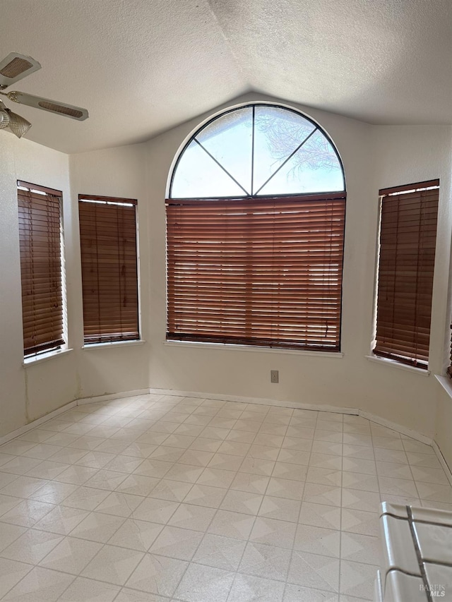 spare room with a textured ceiling, lofted ceiling, and ceiling fan