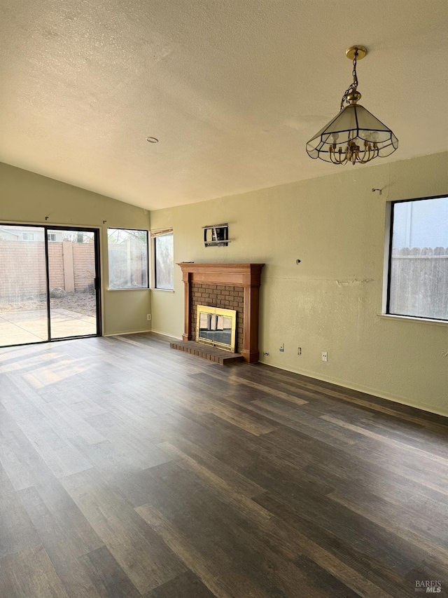 unfurnished living room featuring a textured ceiling, a fireplace, baseboards, dark wood-style flooring, and vaulted ceiling