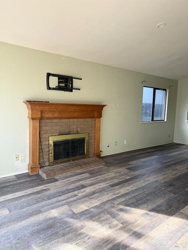 unfurnished living room with a fireplace, baseboards, and wood finished floors