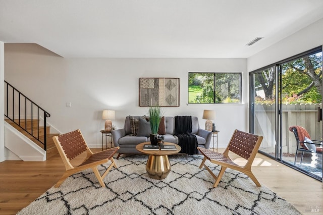 living area with visible vents, baseboards, wood finished floors, and stairs