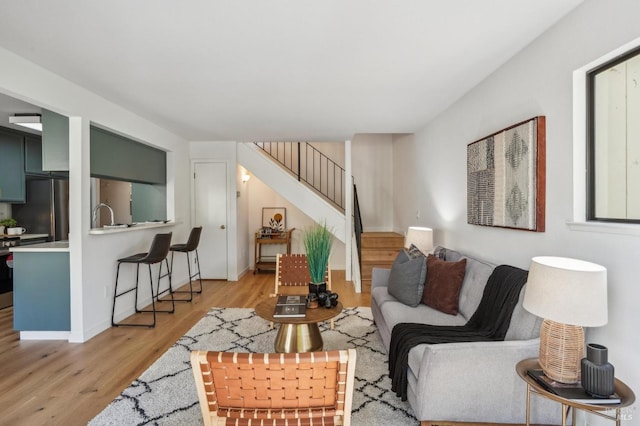 living area with stairs, light wood-type flooring, and baseboards