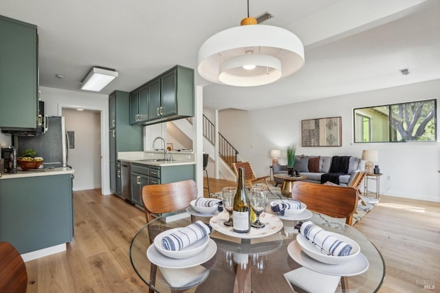 dining space with visible vents, light wood-style flooring, stairs, and baseboards