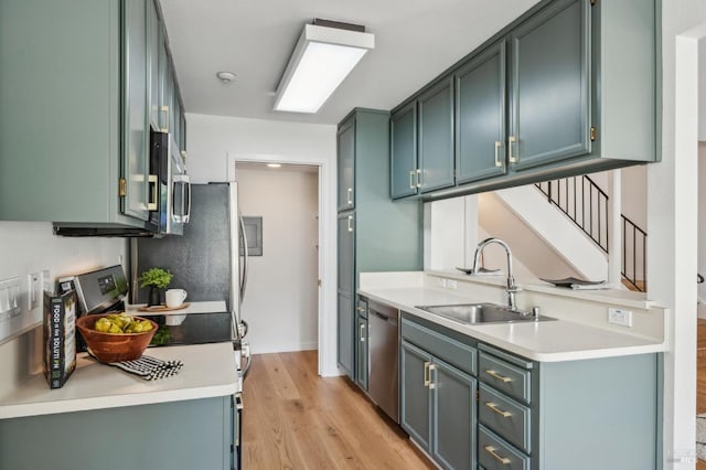 kitchen with light wood-style flooring, appliances with stainless steel finishes, light countertops, and a sink