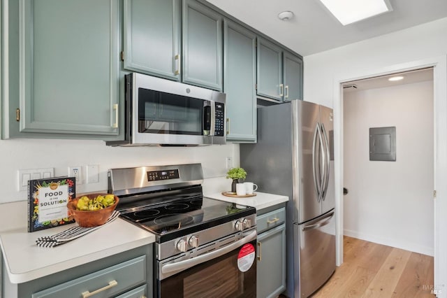 kitchen with electric panel, light countertops, light wood finished floors, and appliances with stainless steel finishes