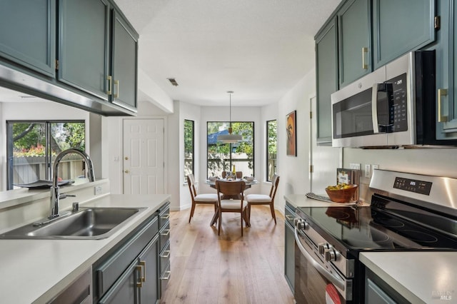 kitchen featuring a sink, light countertops, light wood-style floors, and stainless steel appliances