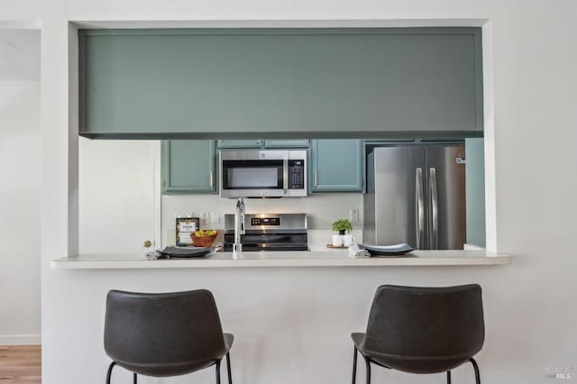 kitchen featuring wood finished floors, appliances with stainless steel finishes, a breakfast bar area, and light countertops