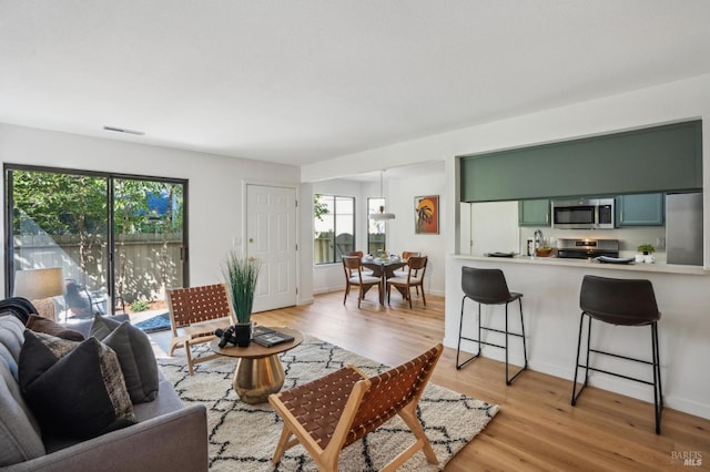 living room with light wood-style floors, visible vents, and baseboards