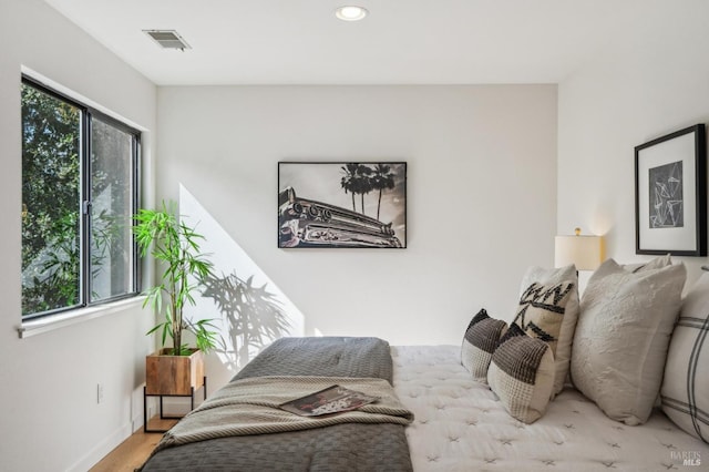 bedroom featuring multiple windows, wood finished floors, visible vents, and baseboards