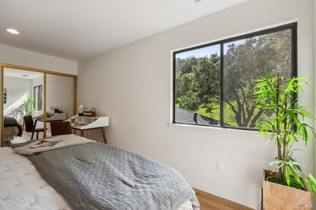 bedroom featuring recessed lighting, baseboards, light wood-type flooring, and a closet