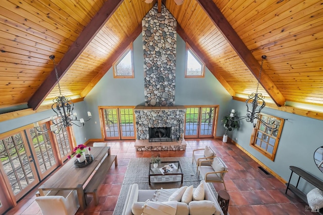 living room with beamed ceiling, plenty of natural light, a stone fireplace, and a chandelier