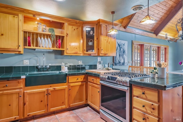 kitchen with visible vents, stainless steel range with gas cooktop, a peninsula, a sink, and hanging light fixtures