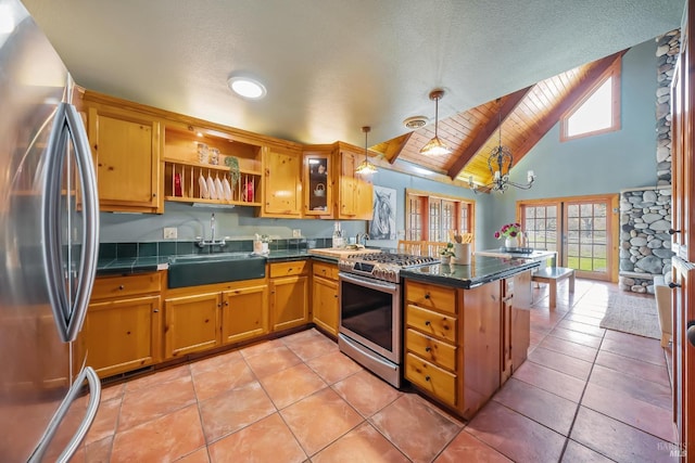 kitchen featuring pendant lighting, a sink, dark countertops, appliances with stainless steel finishes, and a peninsula