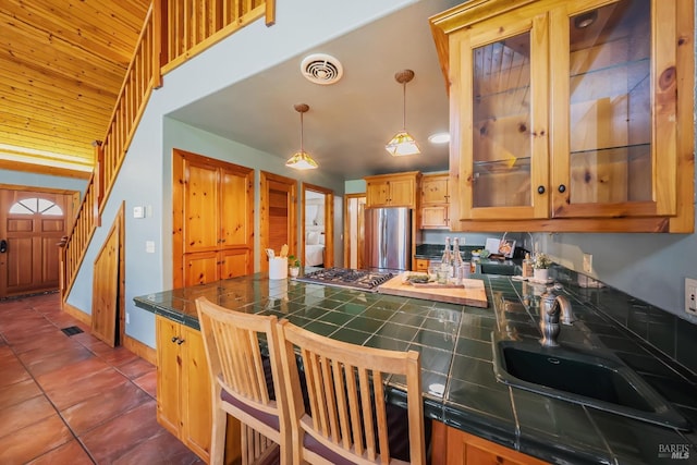 kitchen featuring visible vents, glass insert cabinets, dark tile patterned floors, appliances with stainless steel finishes, and a sink