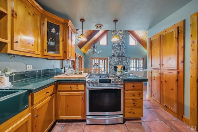 kitchen featuring stainless steel gas range, a peninsula, hanging light fixtures, glass insert cabinets, and a notable chandelier