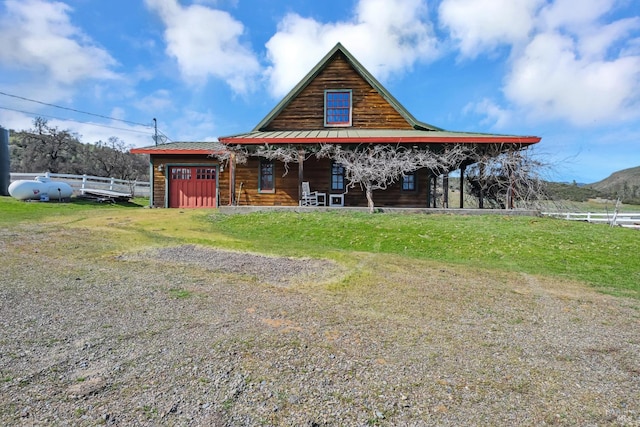 view of front facade with fence, driveway, covered porch, a garage, and metal roof