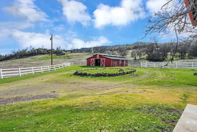 view of yard with an outbuilding, a rural view, a barn, and fence