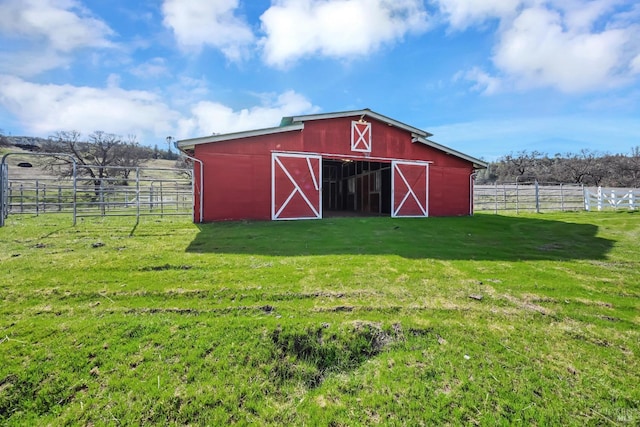 view of barn featuring a rural view, a yard, and fence