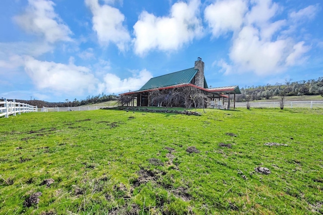 view of yard with a rural view, a barn, fence, and an outbuilding