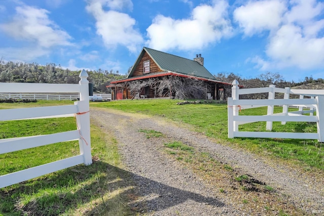 view of property exterior with a barn, a lawn, metal roof, and fence