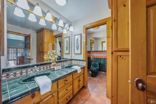 full bath with toilet, a sink, tile walls, tile patterned flooring, and double vanity