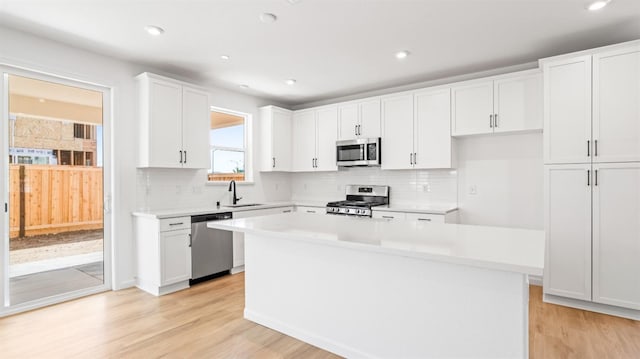 4040 Molten Creek Way, Roseville, CA 95747 - kitchen featuring stainless steel appliances, a sink, a kitchen island, white cabinets, and light wood finished floors