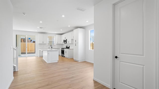 4040 Molten Creek Way, Roseville, CA 95747 - kitchen with stainless steel appliances, a kitchen island, white cabinets, light wood-style flooring, and light countertops
